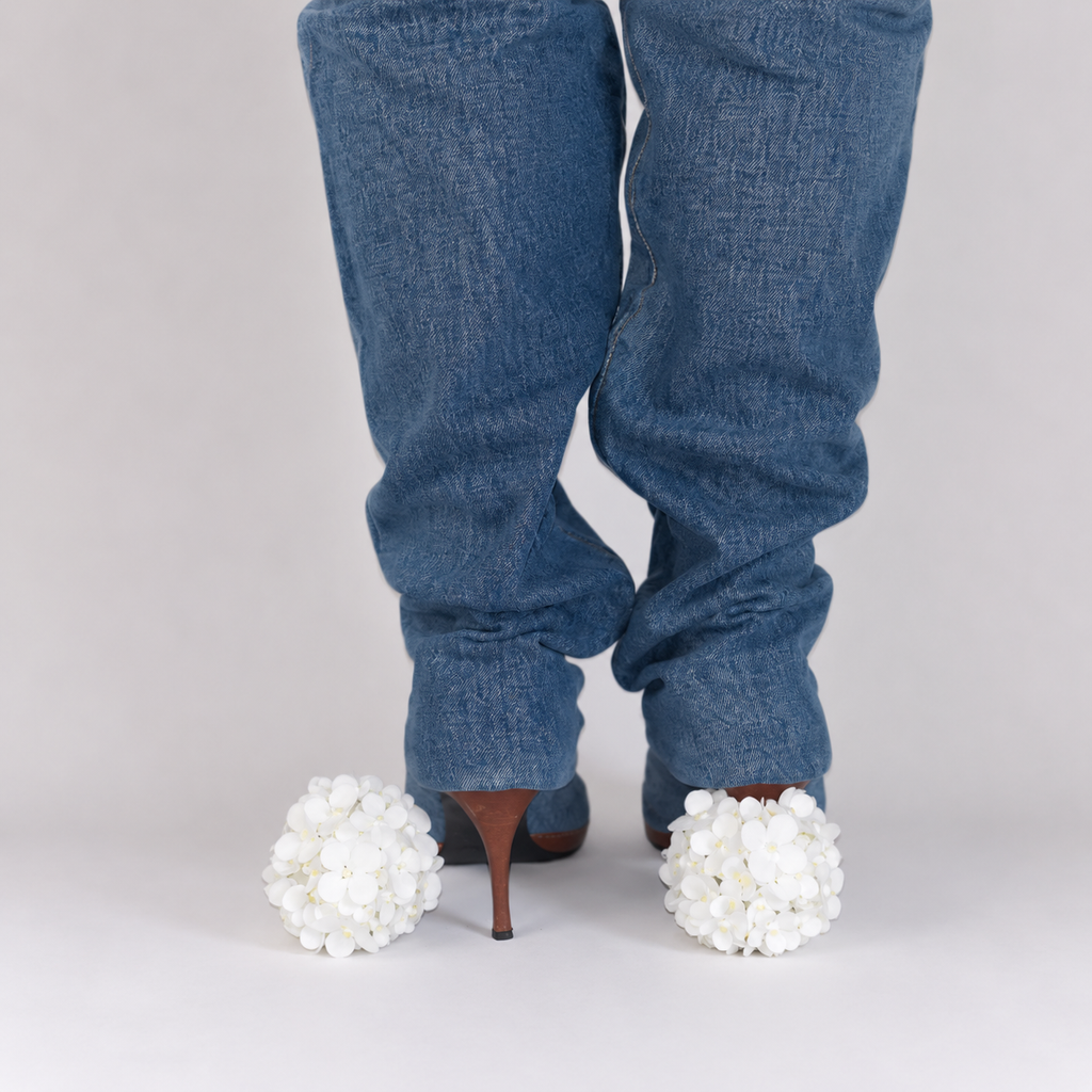 Pair of white hydrangea heel jewels with yellow rhinestones fitted over high heels, rear view